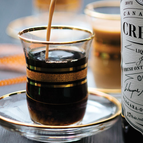 A mixed coffee drink being poured into a clear glass