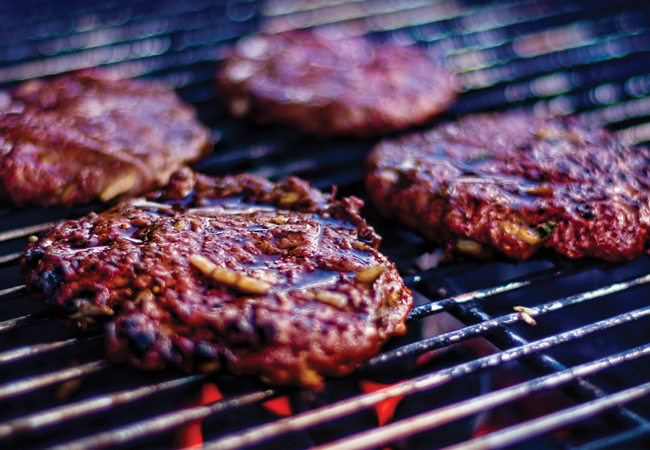 Burgers with barbecue sauce on a grill.