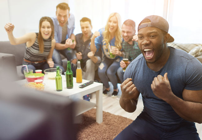 A group of friends cheering while watching the game on TV