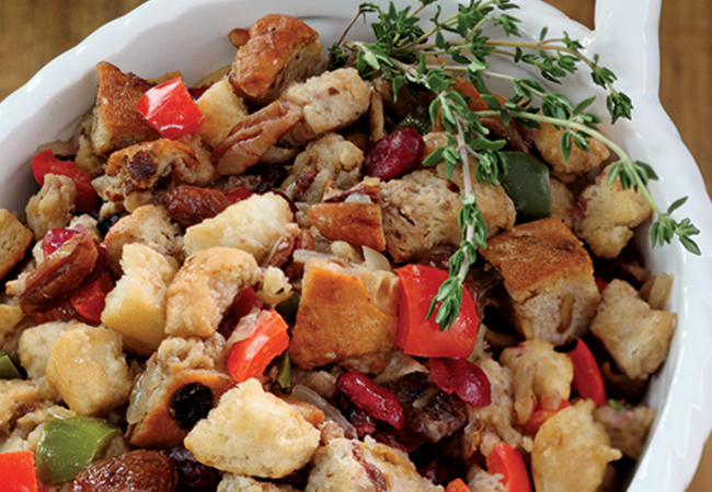 A bowl filled with a variety of breads, vegtables and meats with a thyme garnish