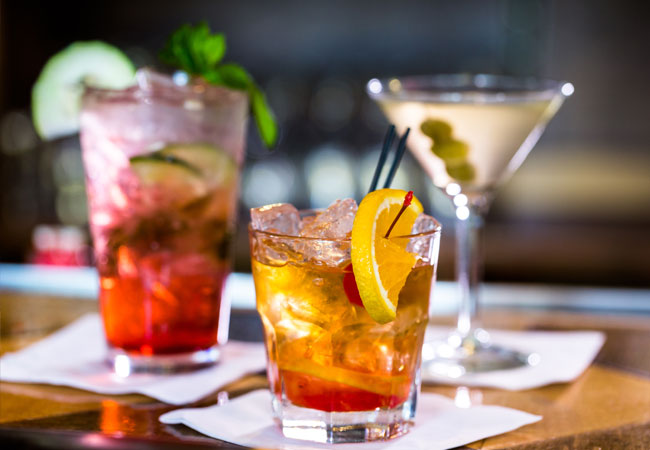 three colourful cocktails sitting on napkins