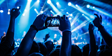 Silhouette of a person holding a phone taking an image at a concert. 