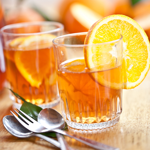 Two glasses of marinade with an orange wedge and cuttlery in the foreground